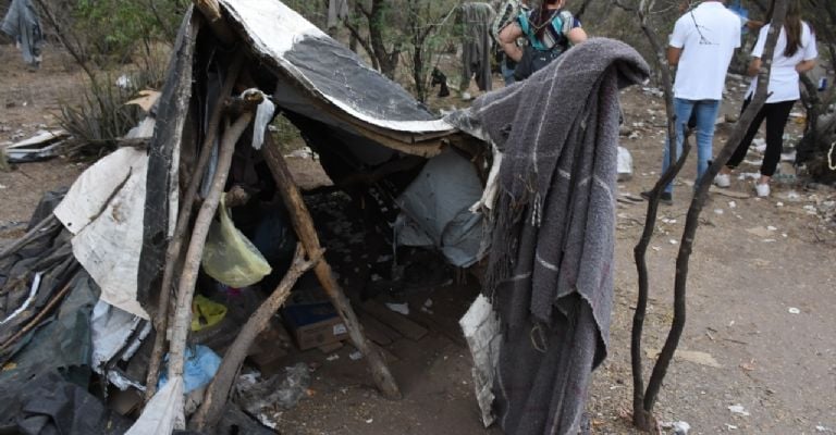 Su casa son palos levantados cubiertos con cobijas, hule negro y lonas