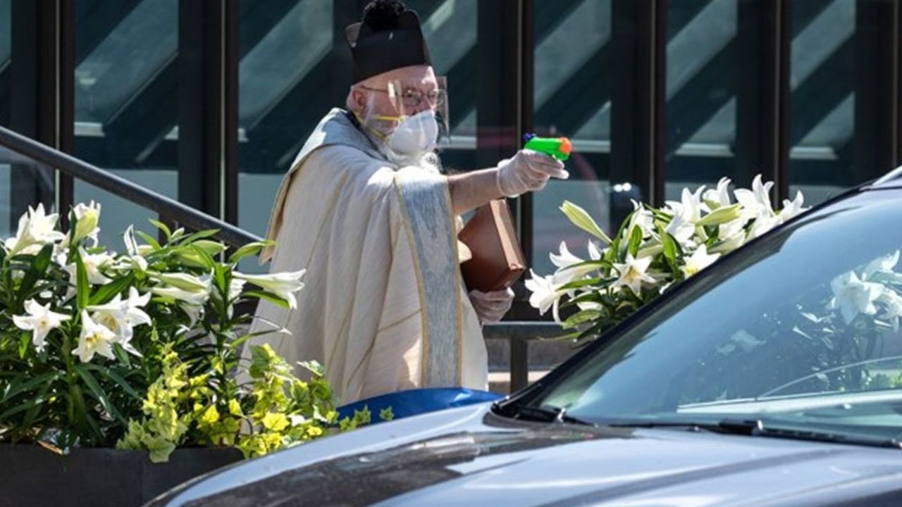 Clérigo da bendición con pistolas de agua bendita para evitar el contacto por Covid-19