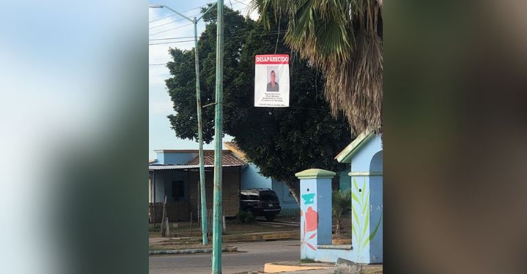 Familiares de víctima colocan ficha de desaparición en la entrada de Villa Bonita