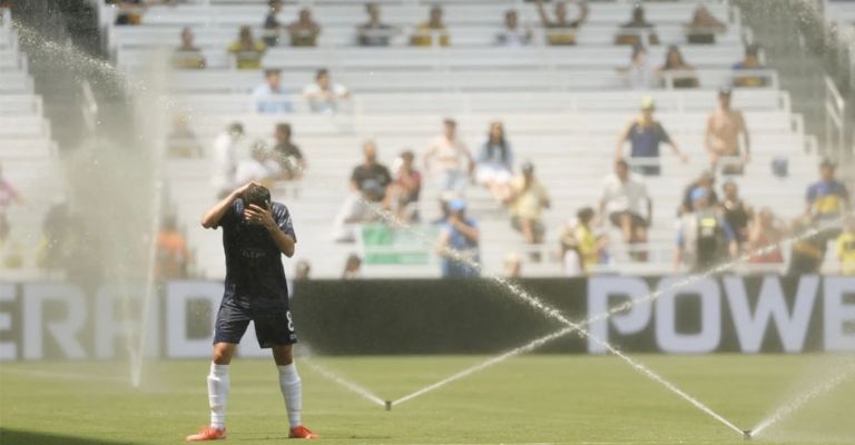 Un jugador del Auckland City se refresca con los aspersores