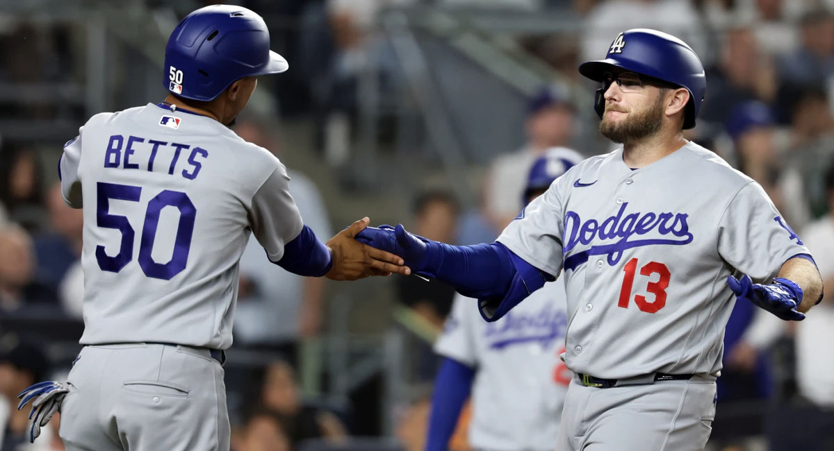 Muncy es felicitado por Betts, después de su jonrón en la séptima entrada